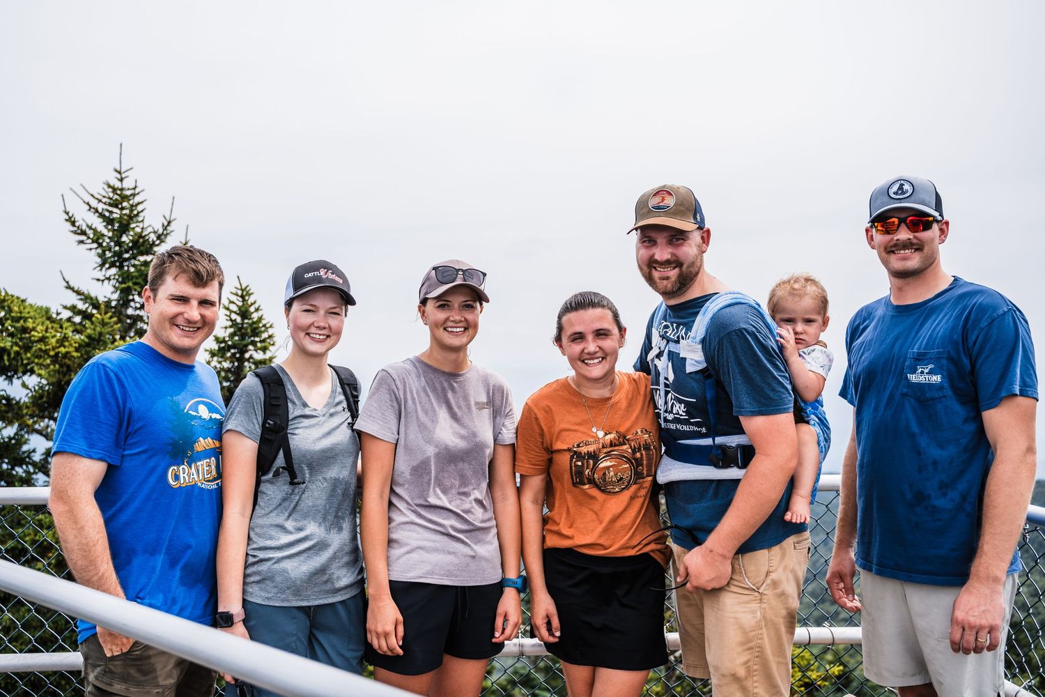 A group of hikers pose together on a mountain overlook during their trek.