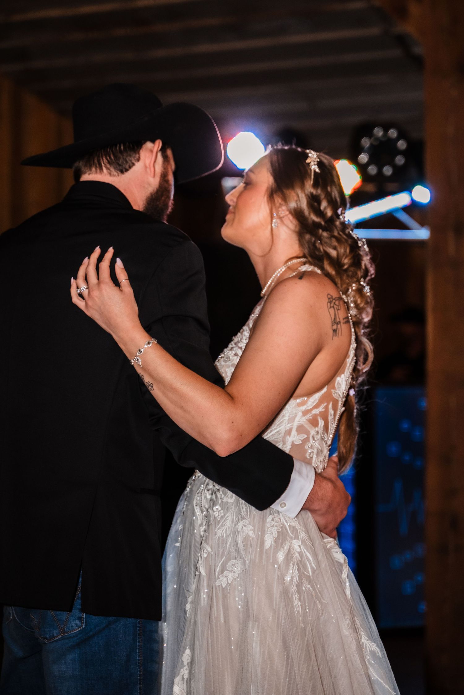 A couple shares an intimate dance together at their wedding reception with blue lights in the background.