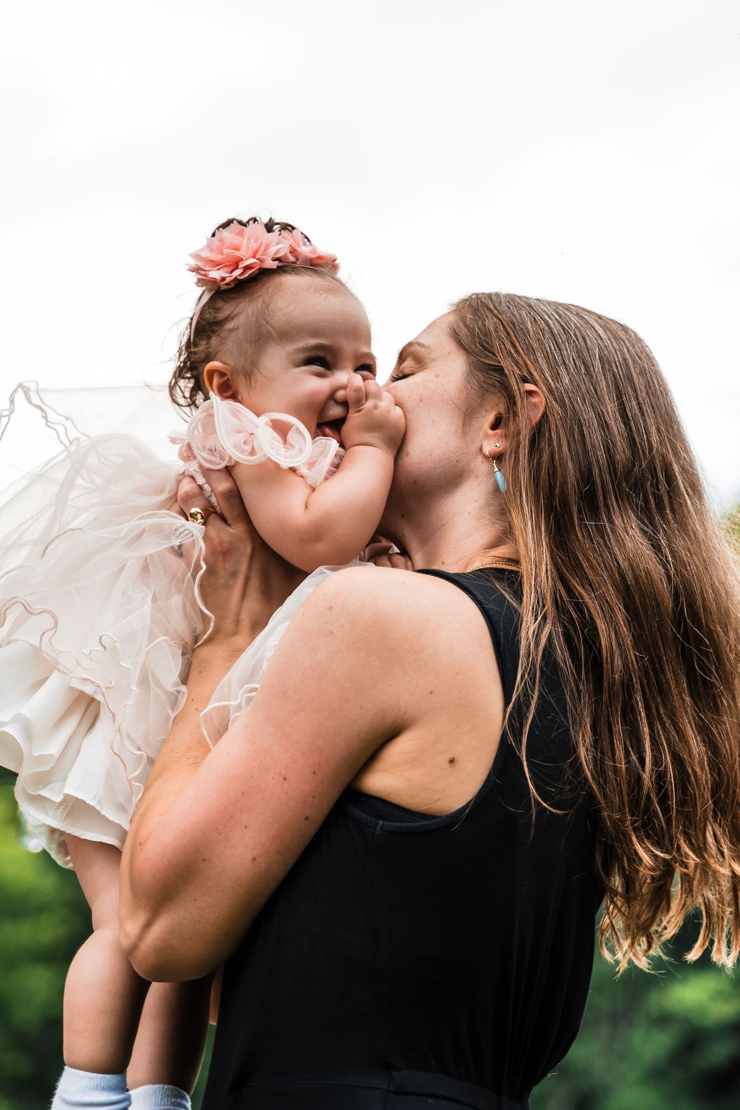 A tender moment captured between parent and baby in a candid outdoor portrait.