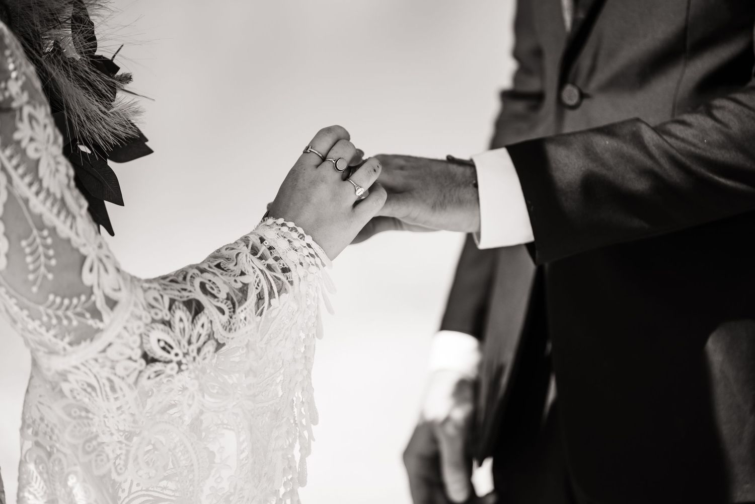 Black and white close-up of hands exchanging wedding rings during an intimate ceremony.