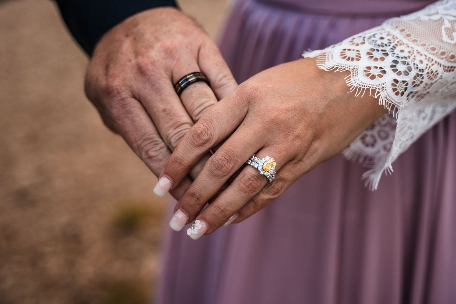 Close-up of hands showing wedding rings against lace and mauve fabric details.