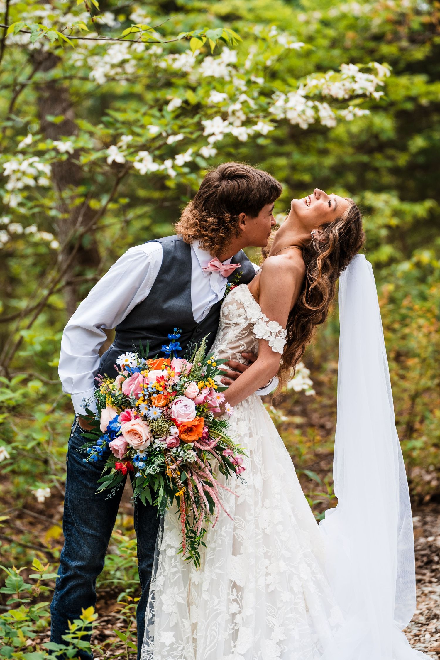 Romantic wedding portrait of couple embracing among blooming dogwood trees.