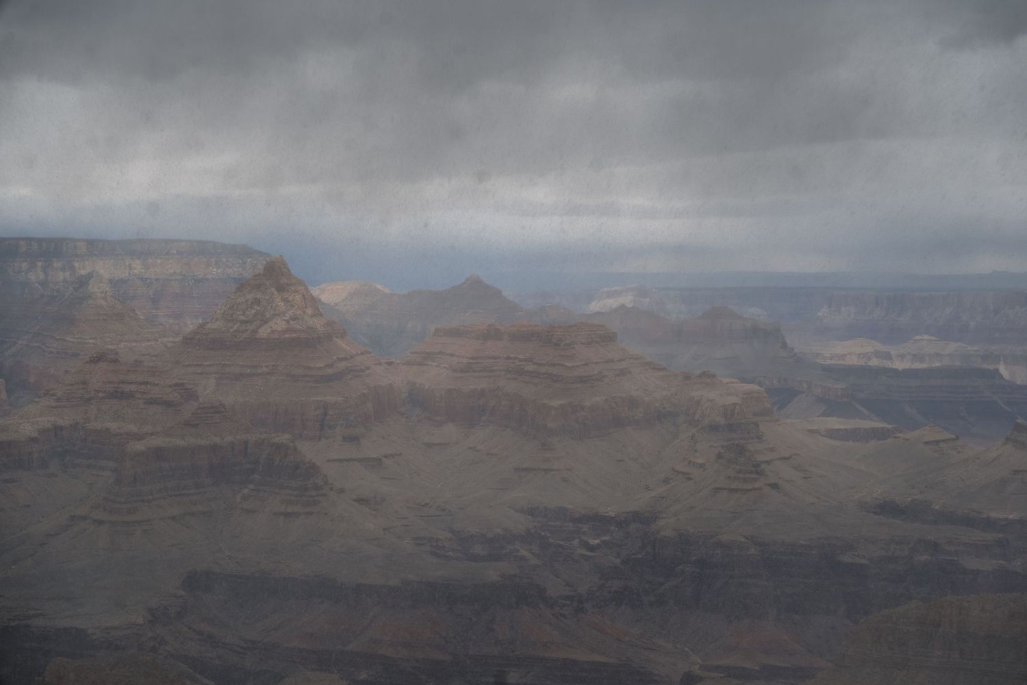 Hazy mountain peaks and ridges of the Grand Canyon stretching into the distance.