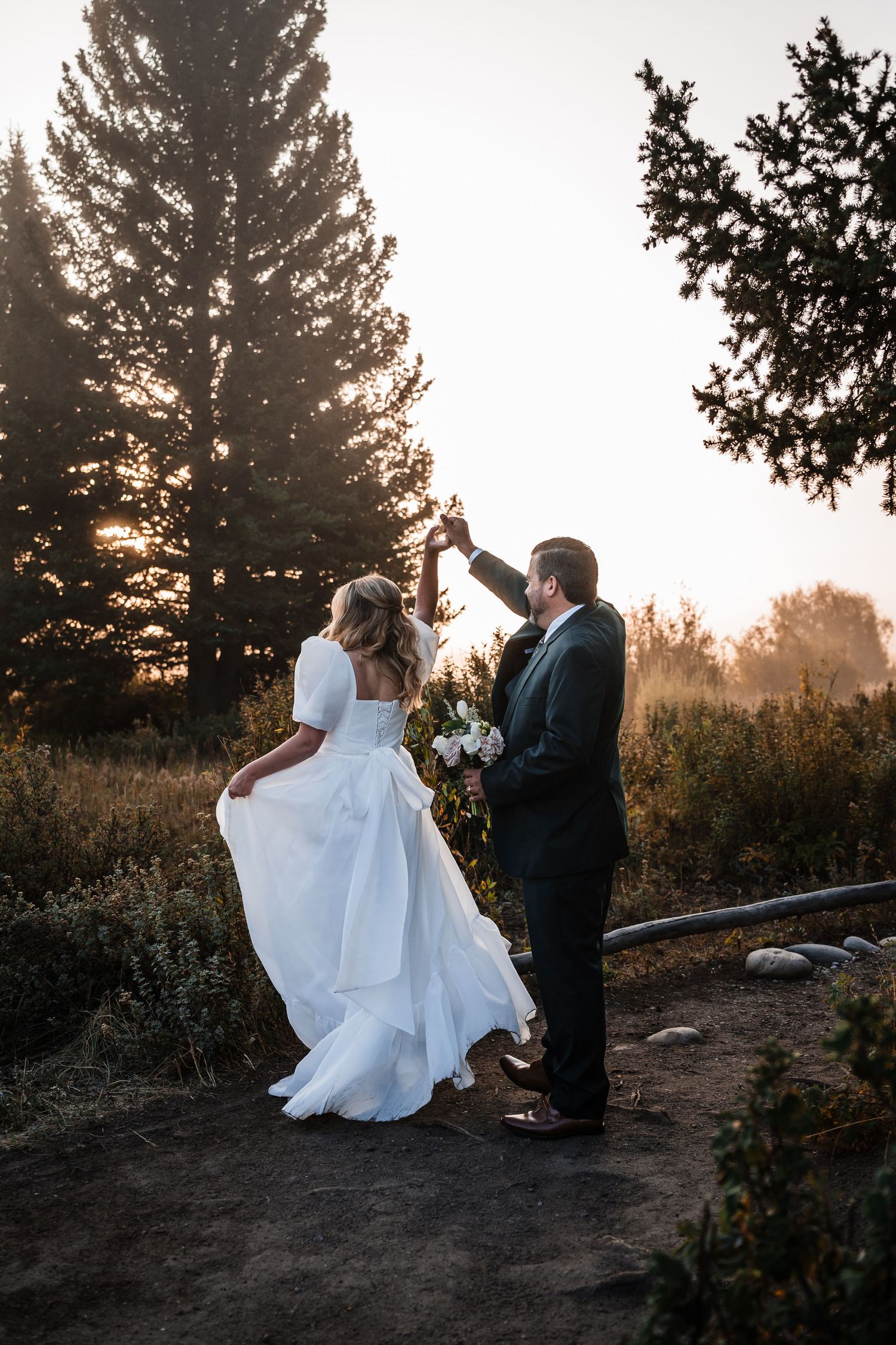 Silhouettes dance against a sunset sky surrounded by tall pine trees.