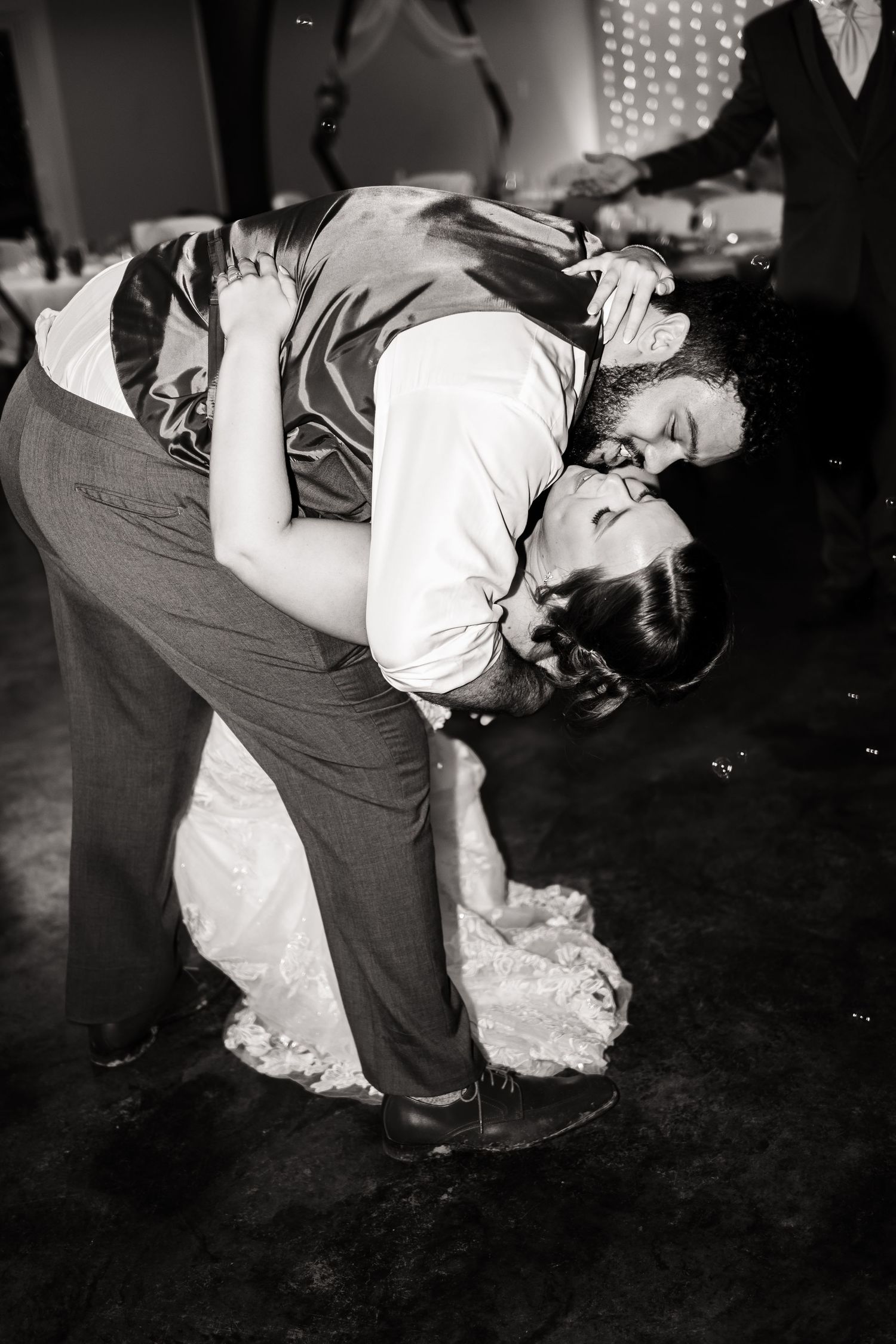 A romantic black and white photo of a couple in a dance dip pose during a wedding reception.