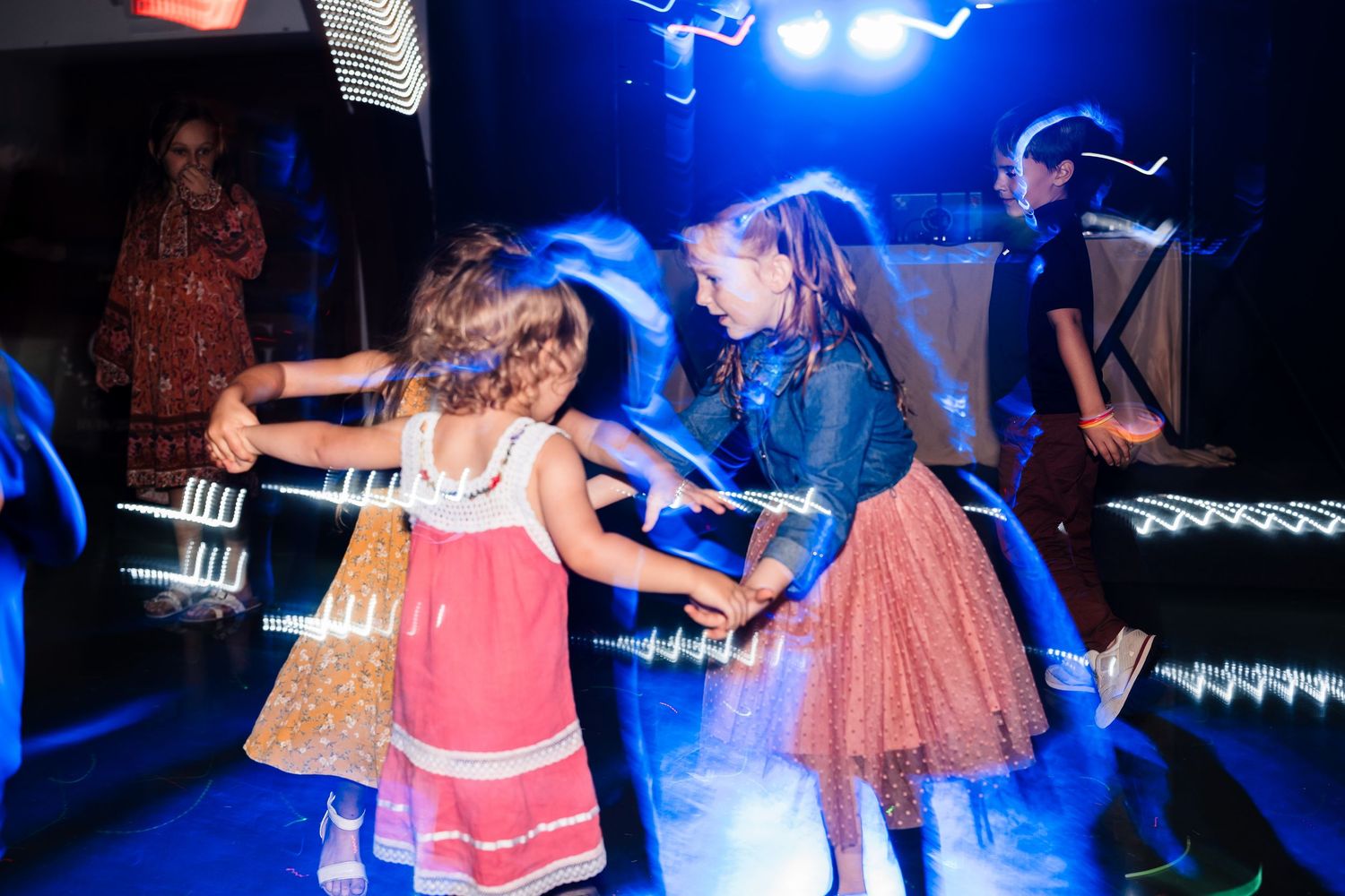 Guests dance and celebrate under blue lighting at a wedding reception party.