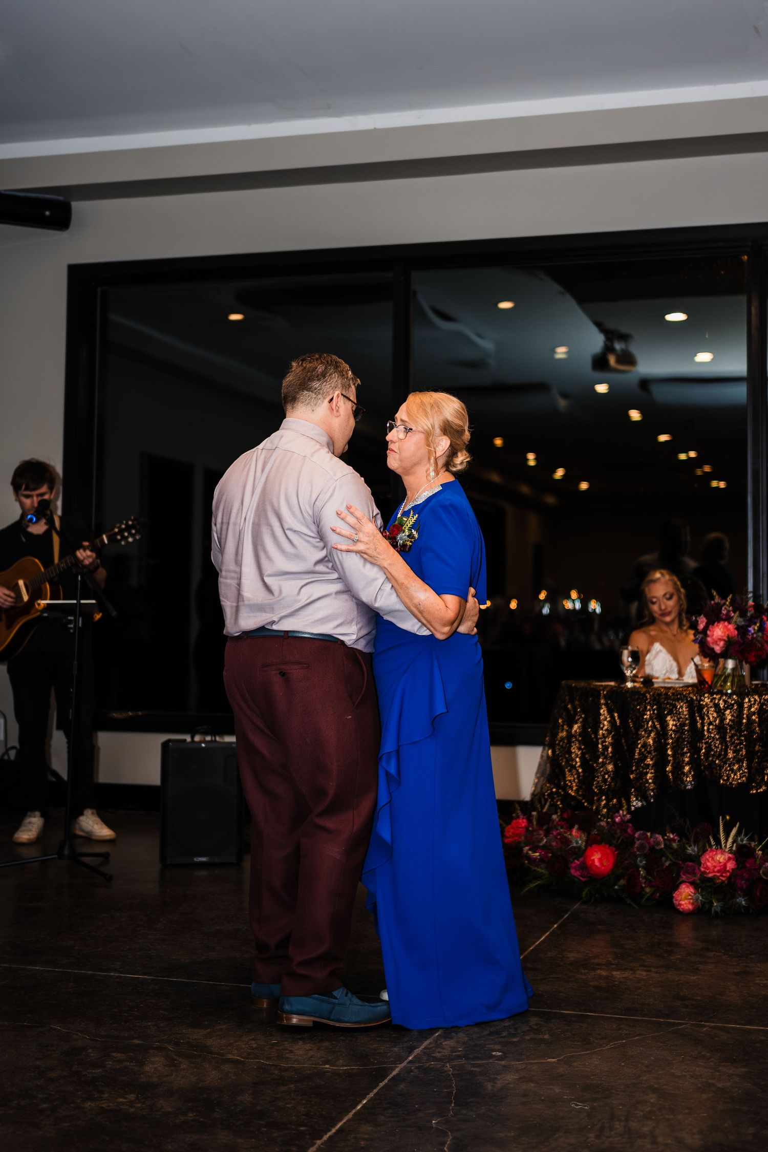 Wedding reception dance floor with guests dancing in formal attire under indoor lighting.