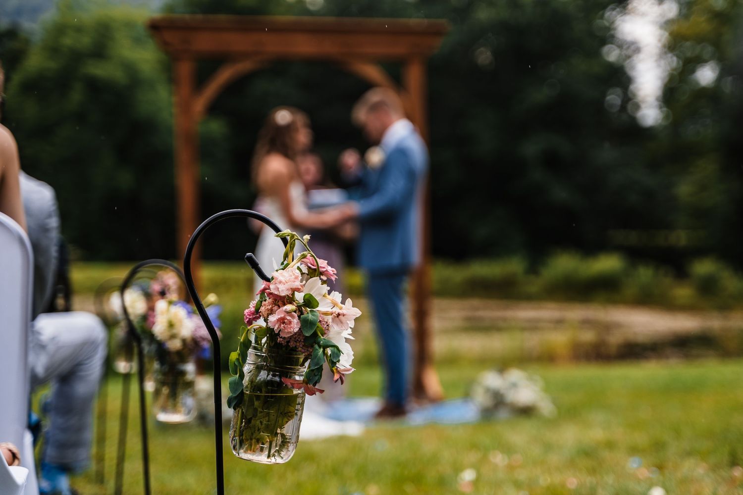 Decorative mason jar with fresh flowers hangs along the wedding ceremony aisle.