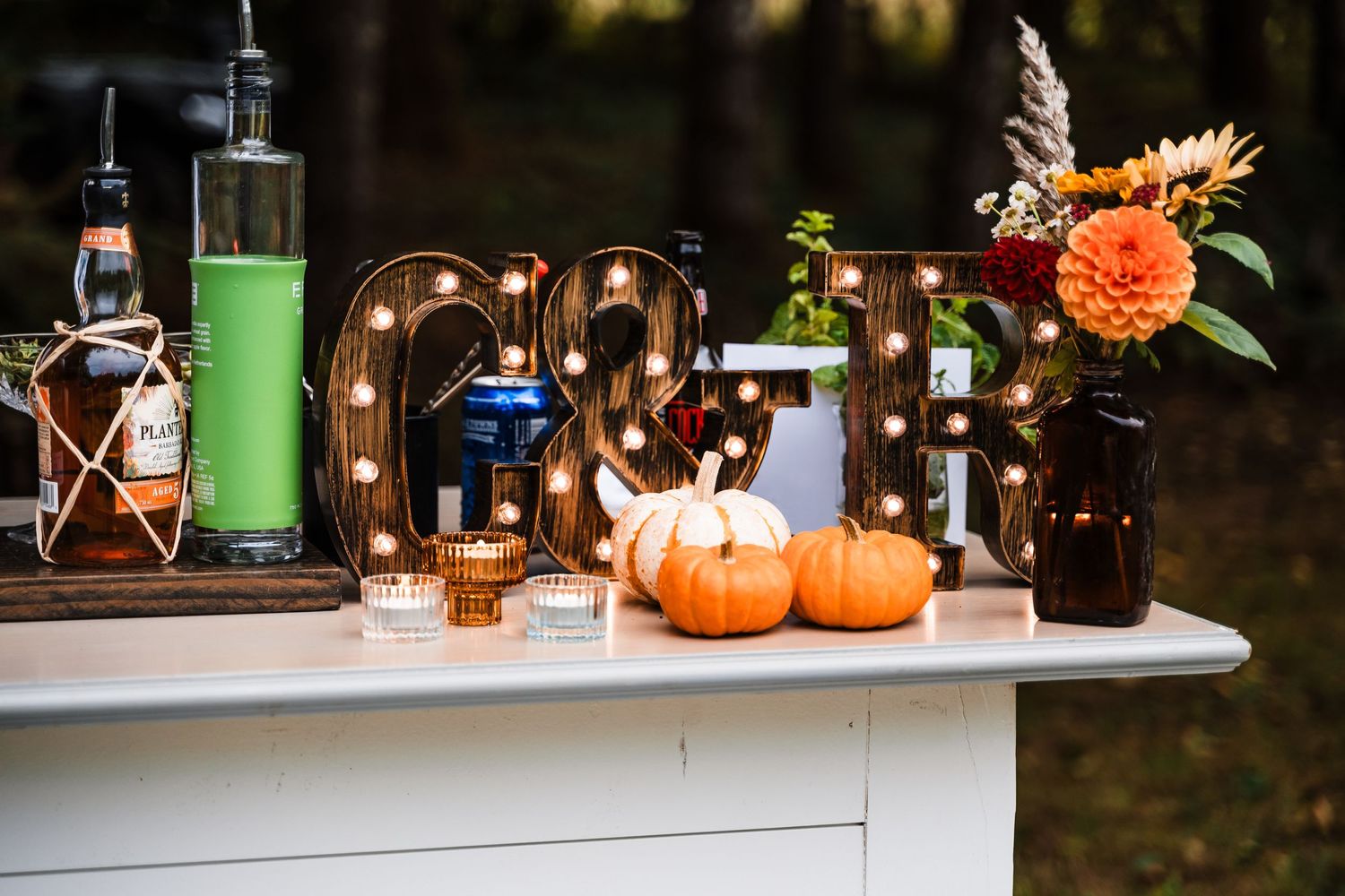 A Halloween-themed bar setup with lit marquee letters, pumpkins, and colorful drinks on display.