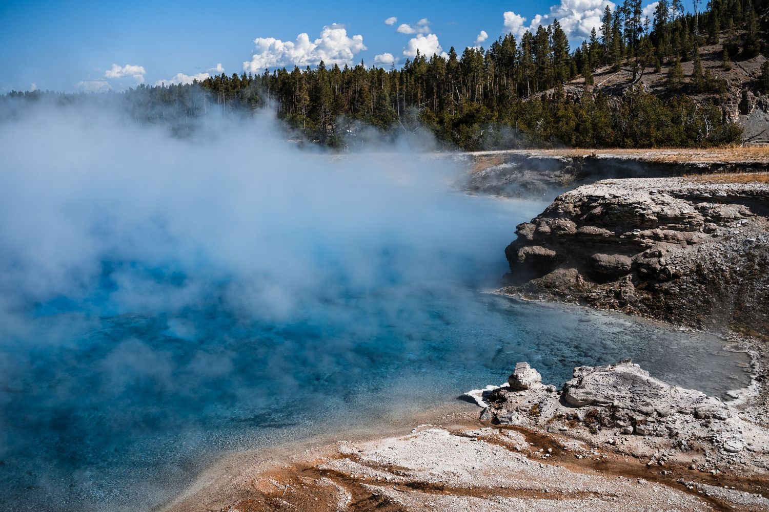 Steaming hot springs and geothermal pools in Yellowstone's volcanic landscape.