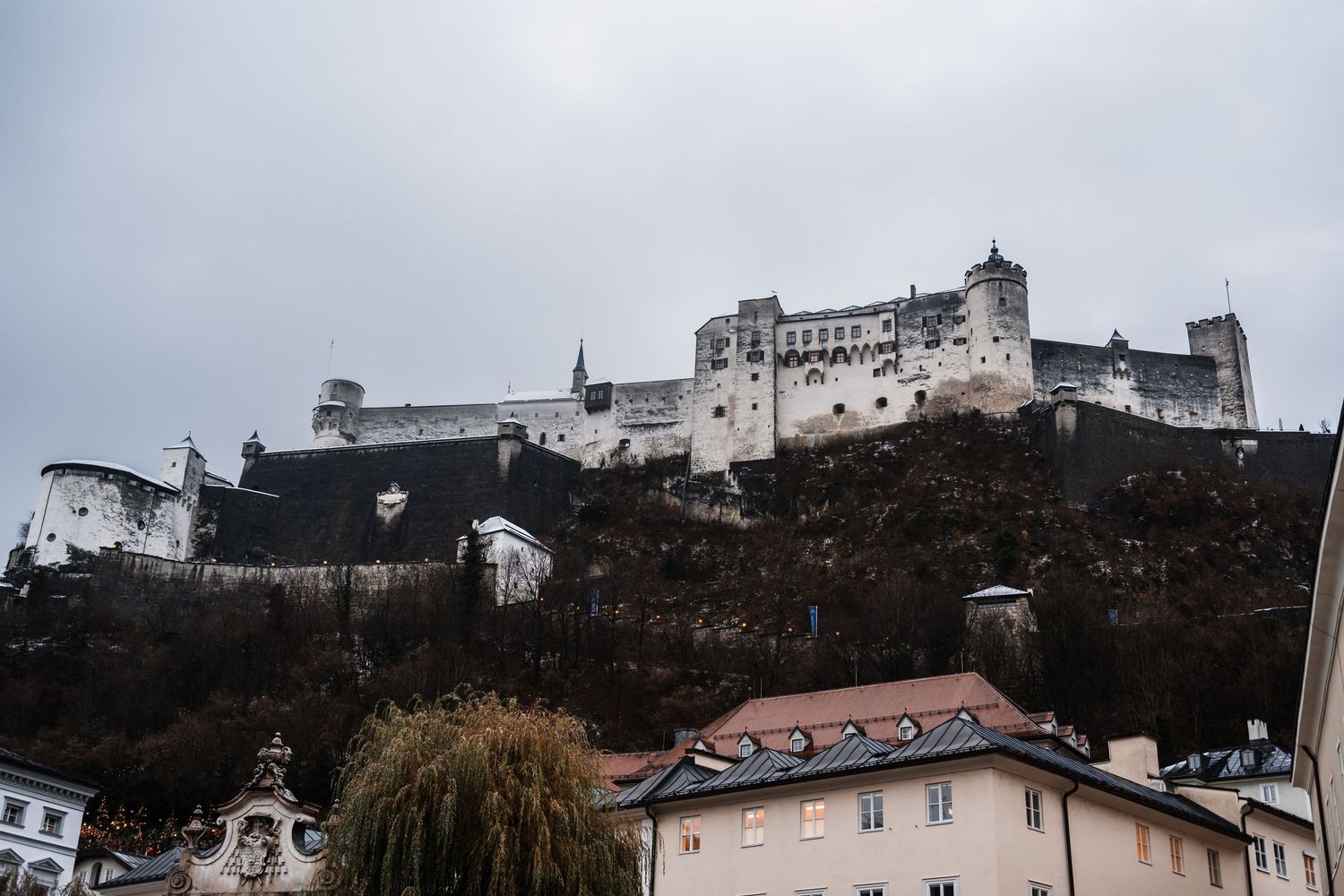 Panoramic view of a hilltop fortress and surrounding buildings in a European town.