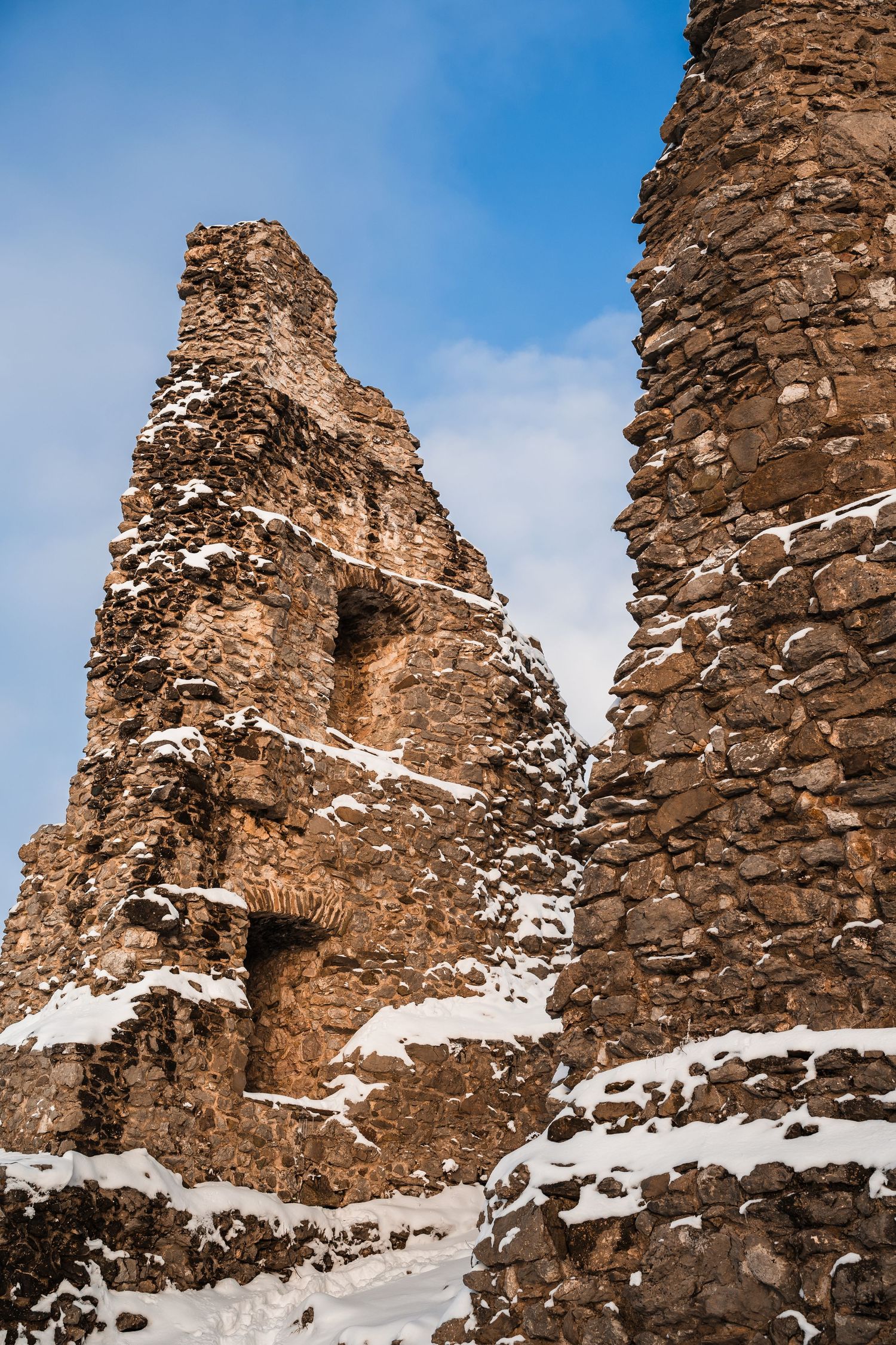 Detailed view of weathered stone castle walls with snow accumulating in the crevices.