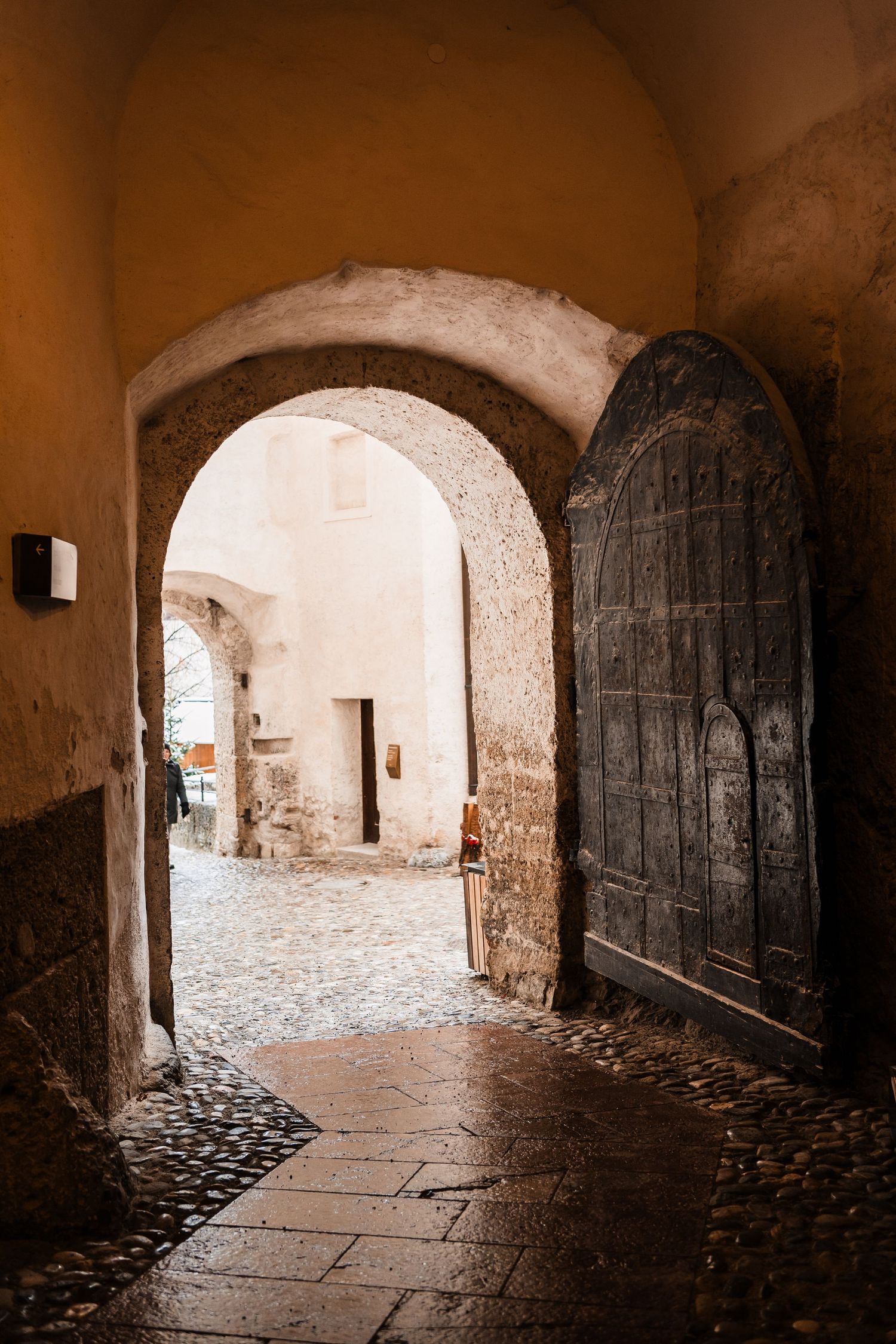 Stone archways with cobblestone floors lead down a dimly lit medieval corridor.