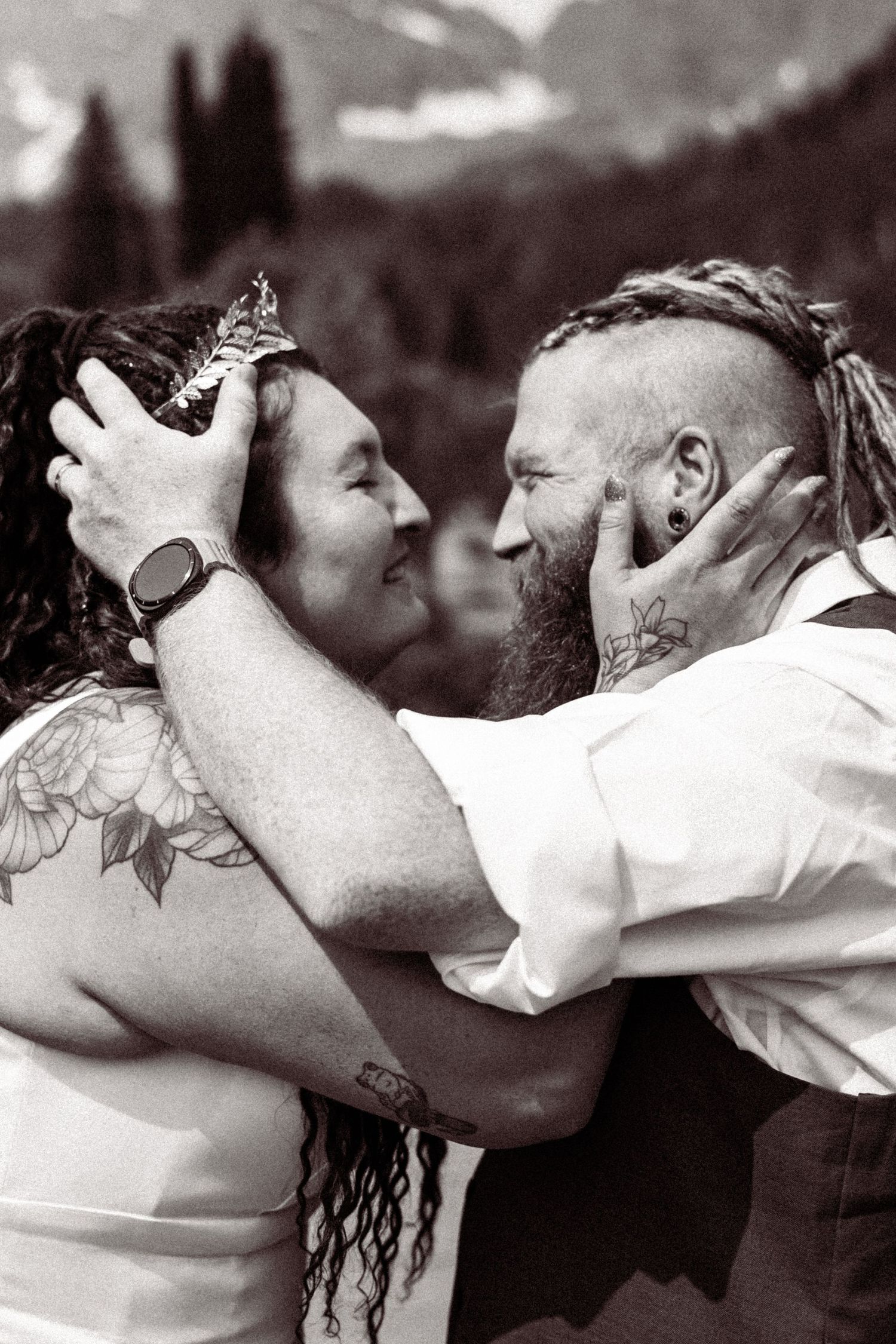 Black and white photo of tattooed couple embracing and smiling at mountain elopement ceremony.