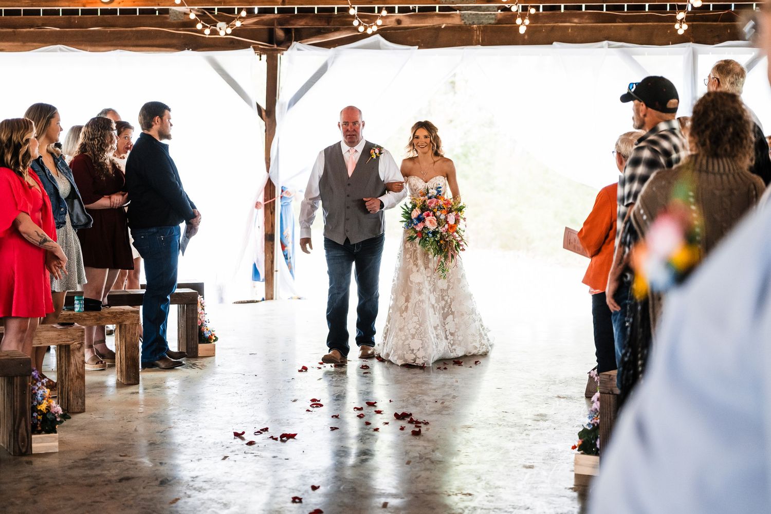 A wedding ceremony in a rustic pavilion with guests gathering around to witness the special moment.