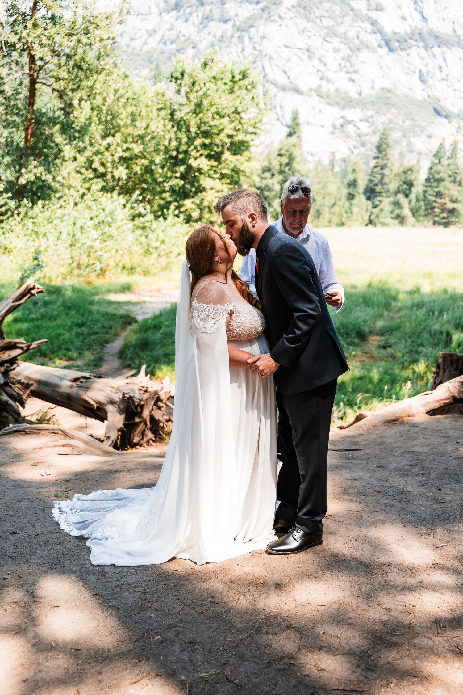 A couple shares tender first look moments in their wedding attire against a scenic mountain landscape backdrop.