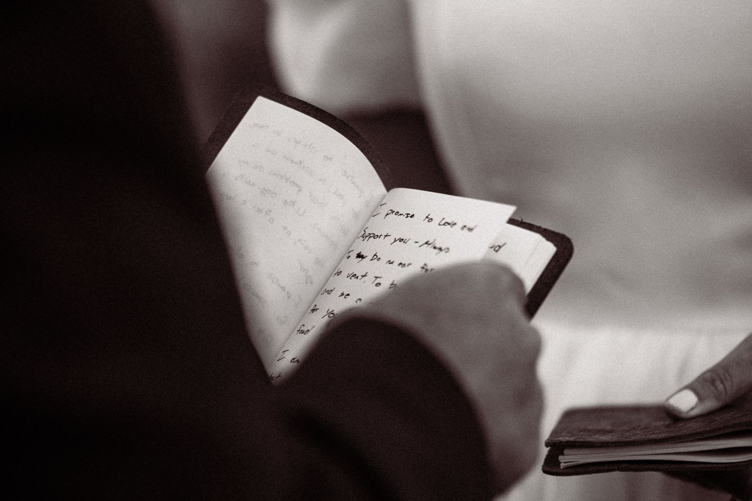 Black and white close-up of handwritten wedding vows on paper with soft focus.