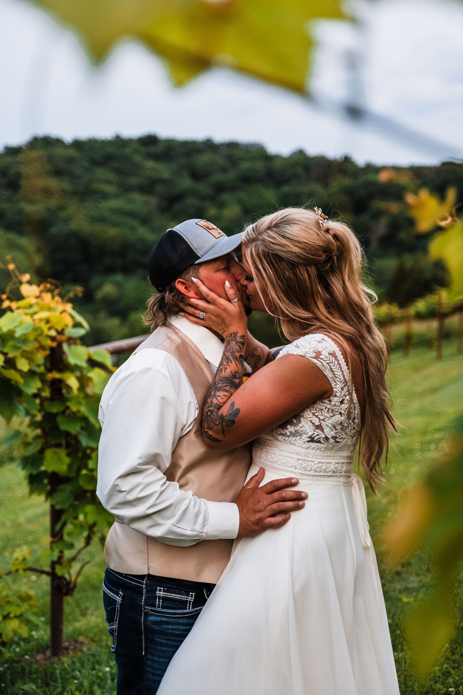 Intimate moment between couple amidst vineyard setting during sunset wedding celebration.