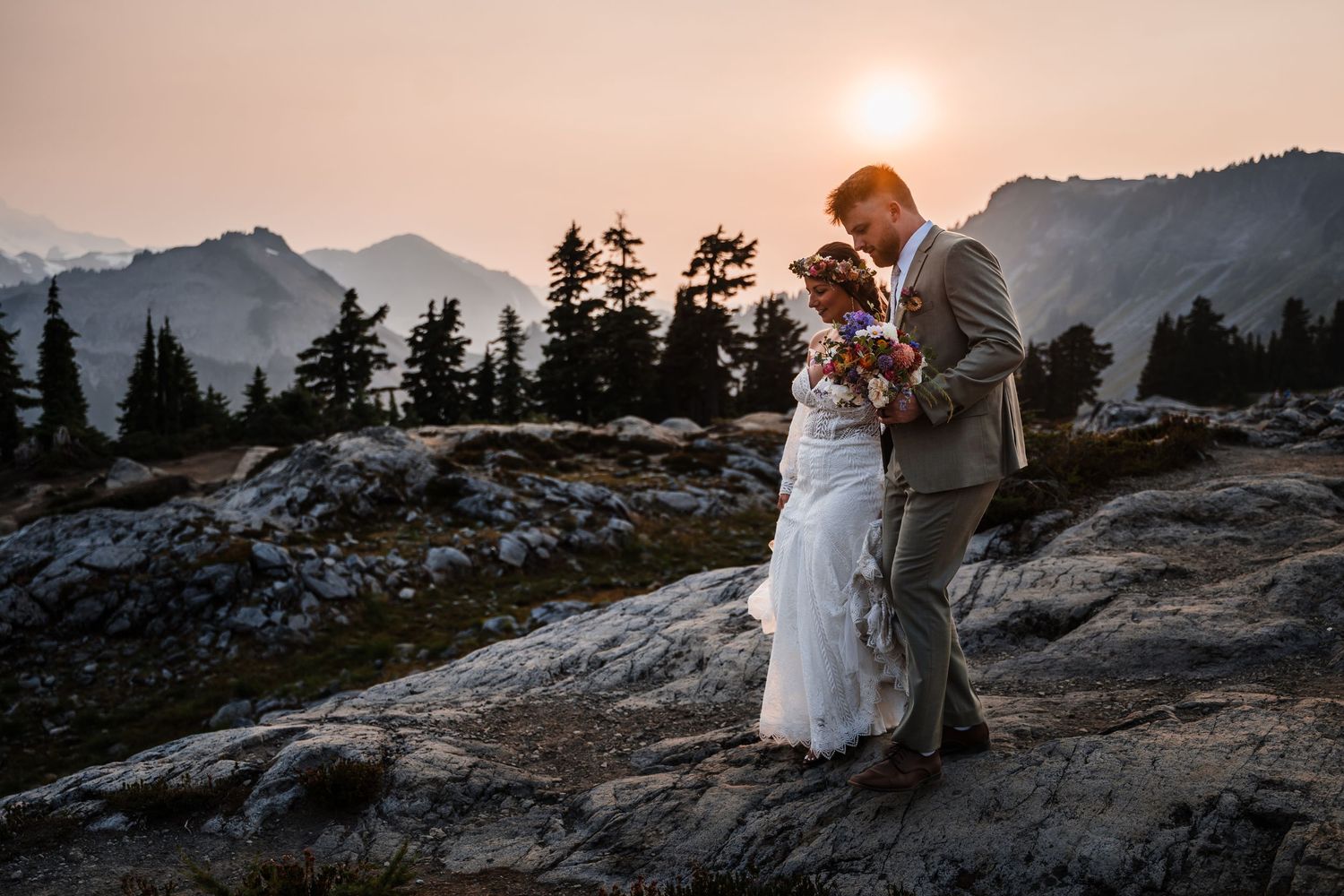 Couple sharing intimate moment at sunset with mountain vista in background.