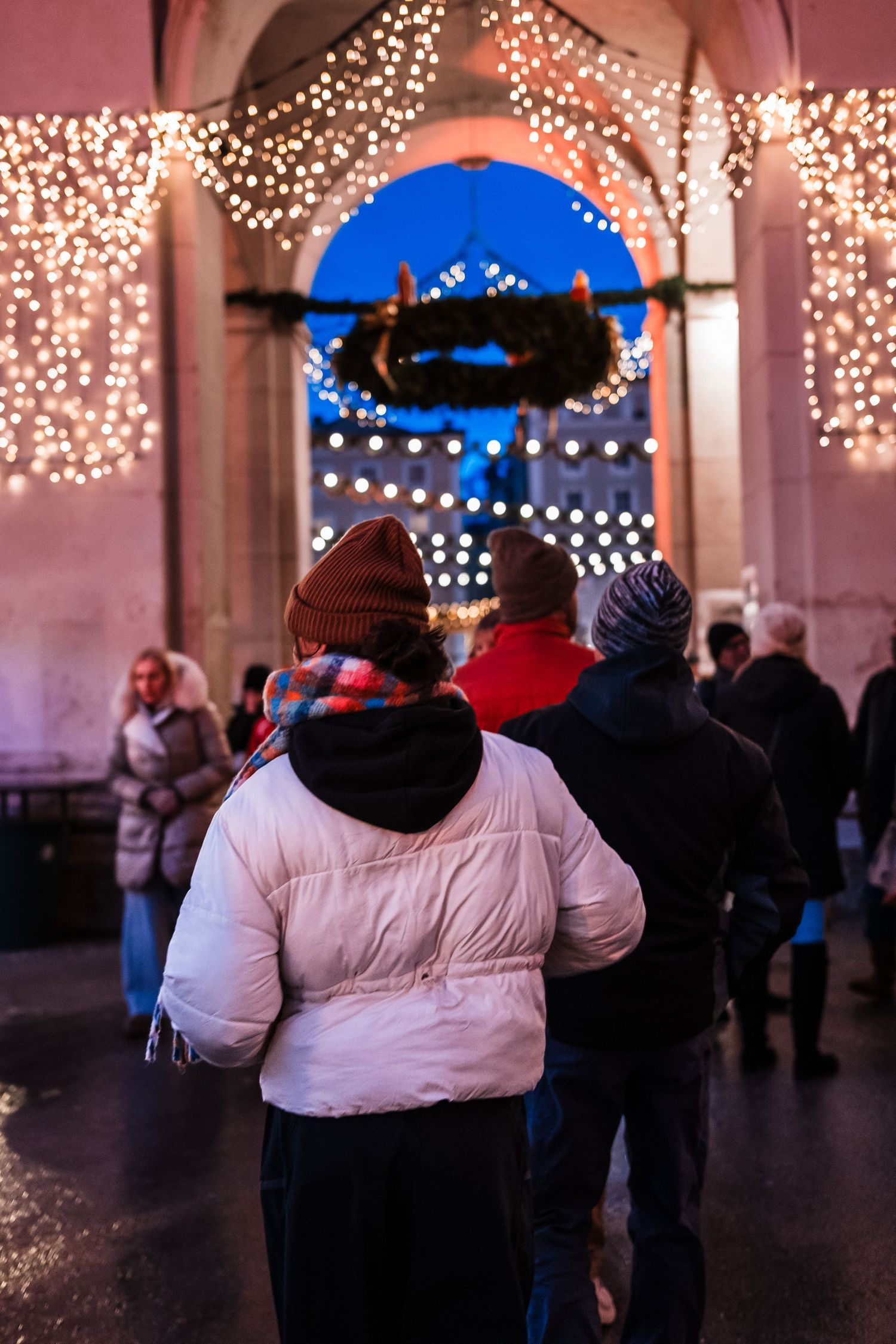 Crowd enjoying an evening gathering under twinkling string lights at an outdoor venue.
