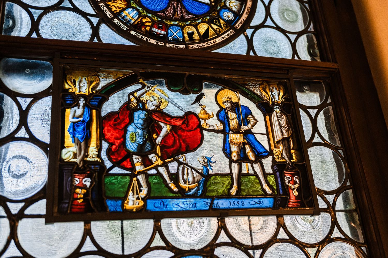 Medieval stained glass window panels depicting religious scenes with ornate details and vibrant colors.