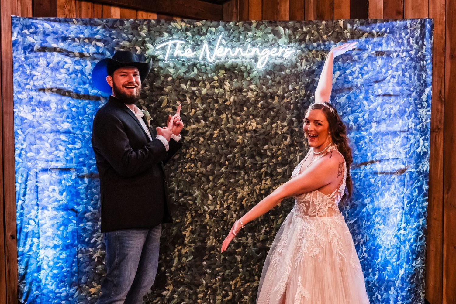 A couple dances in front of a sparkly backdrop illuminated by blue lighting at their wedding reception.
