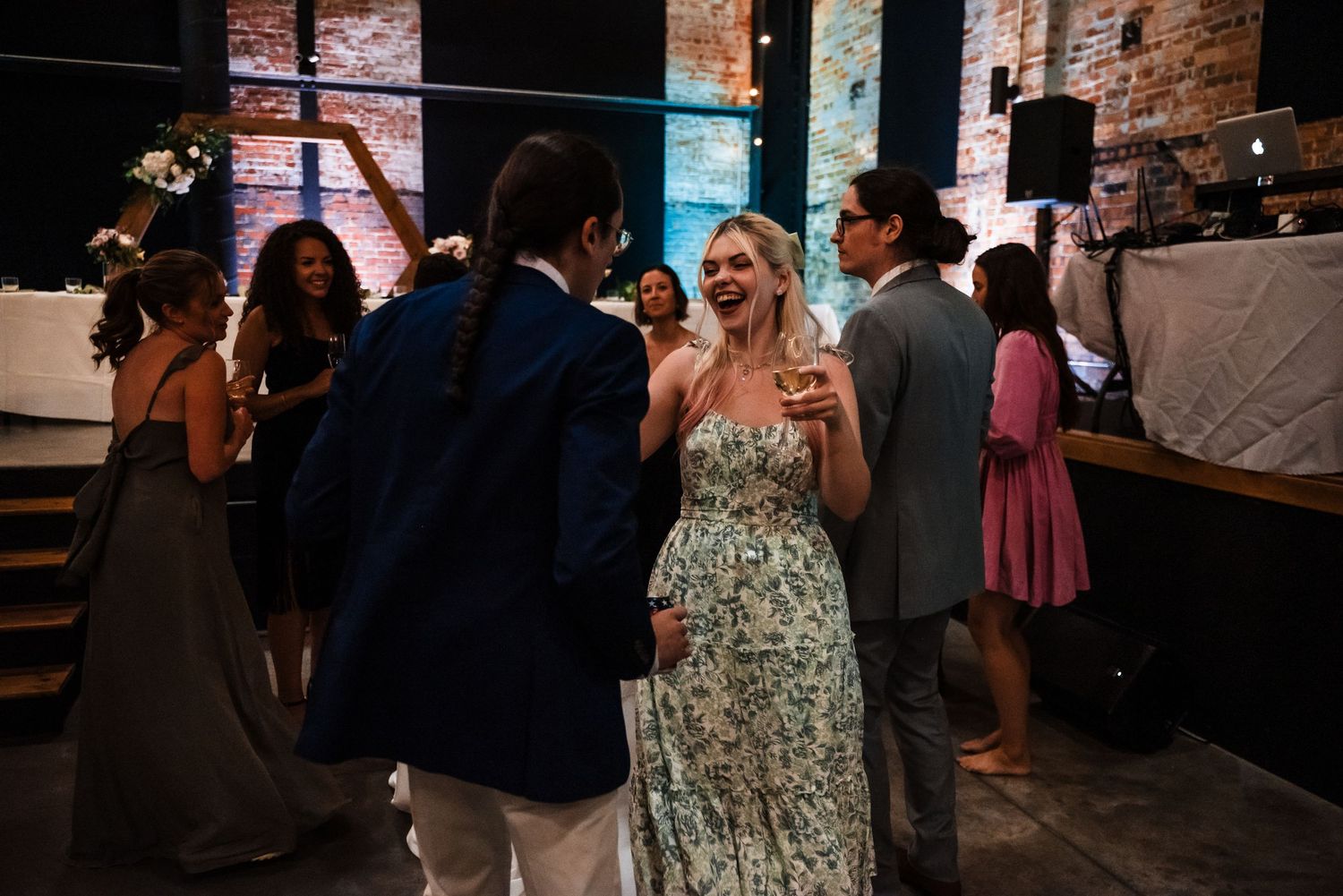Wedding reception scene with guests mingling under indoor string lights.