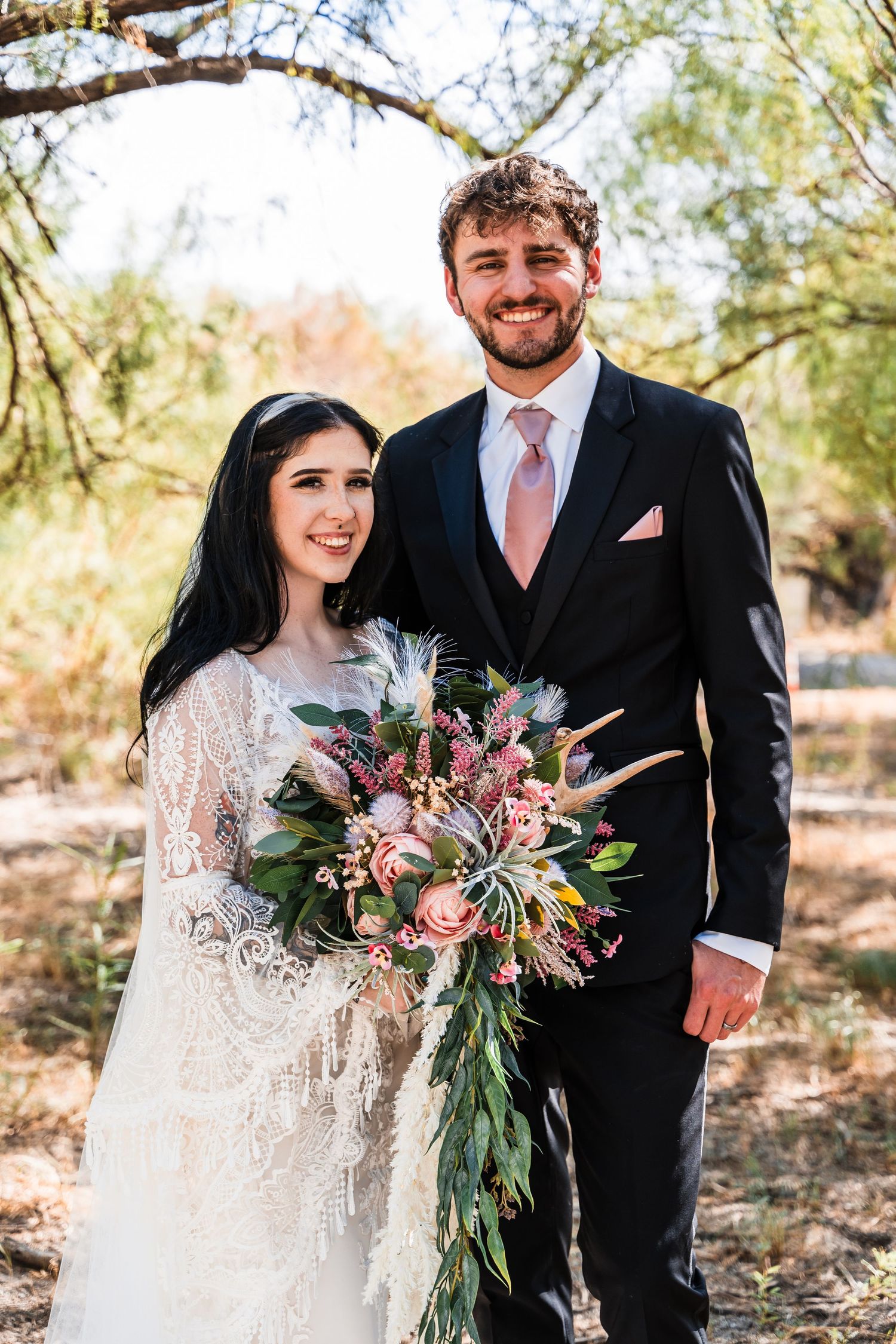 A lovely outdoor wedding portrait featuring a couple with a stunning desert-inspired bouquet.