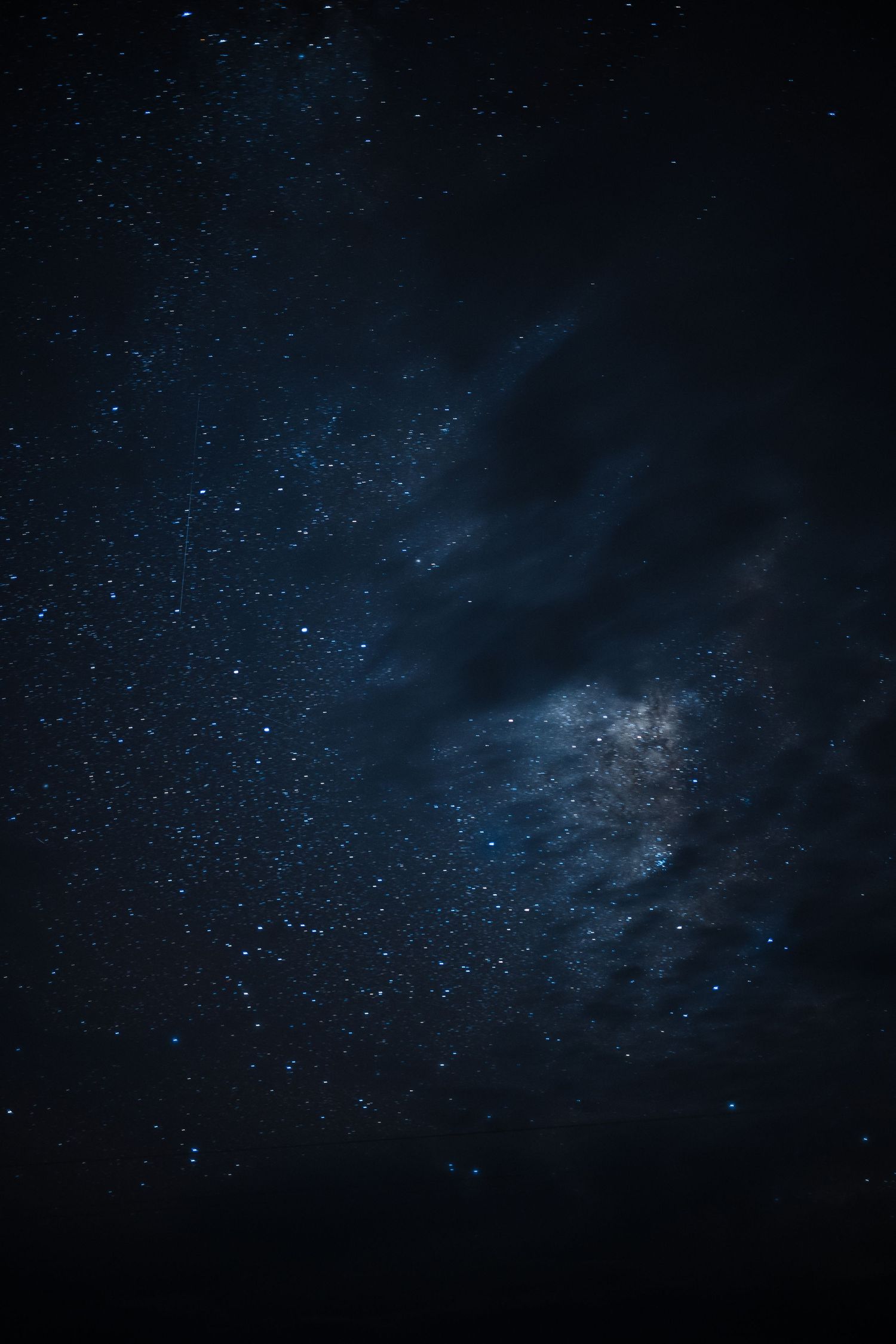 A dark night sky filled with twinkling stars and blue cosmic clouds.