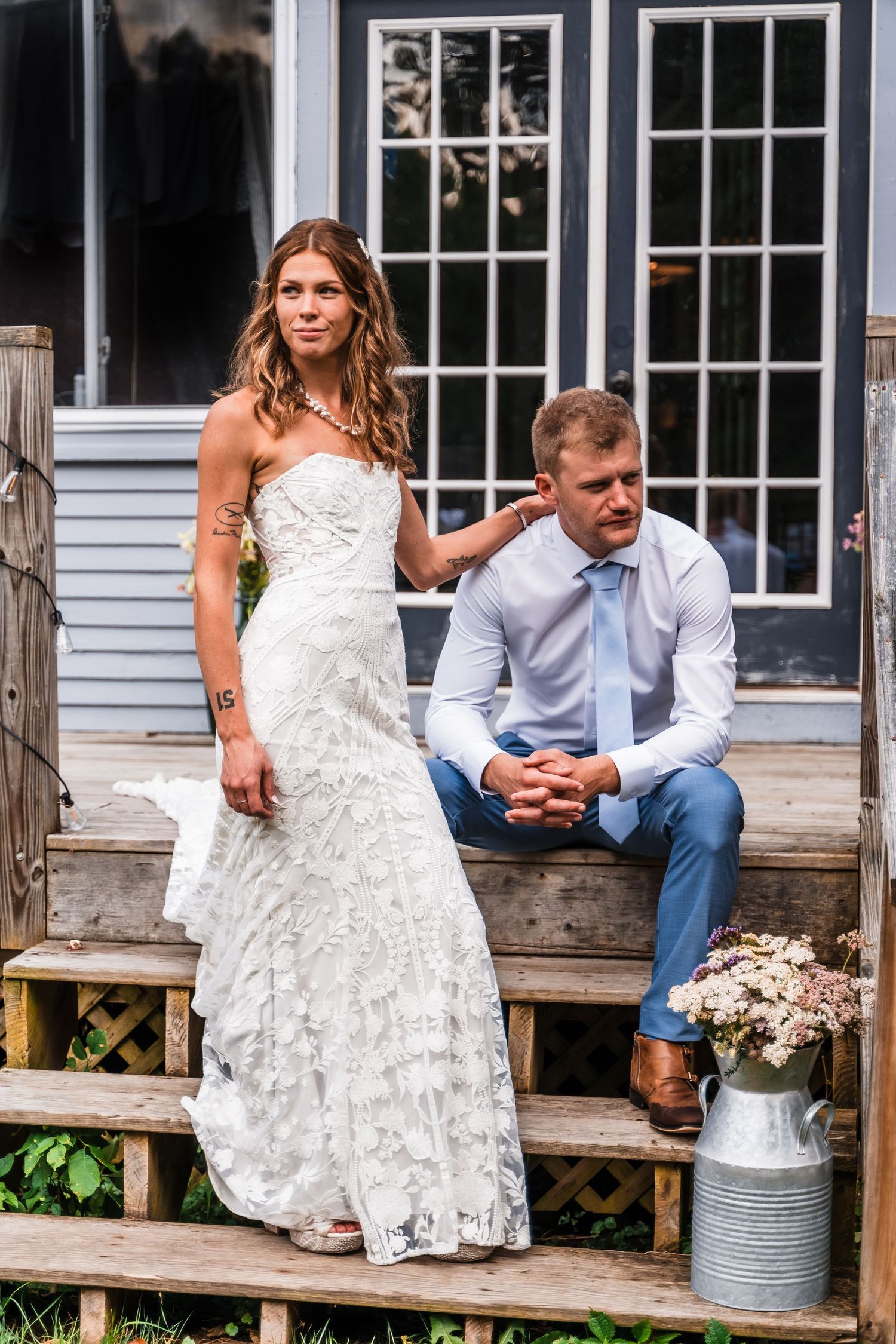 A couple sitting on wooden steps outside a house with French doors.