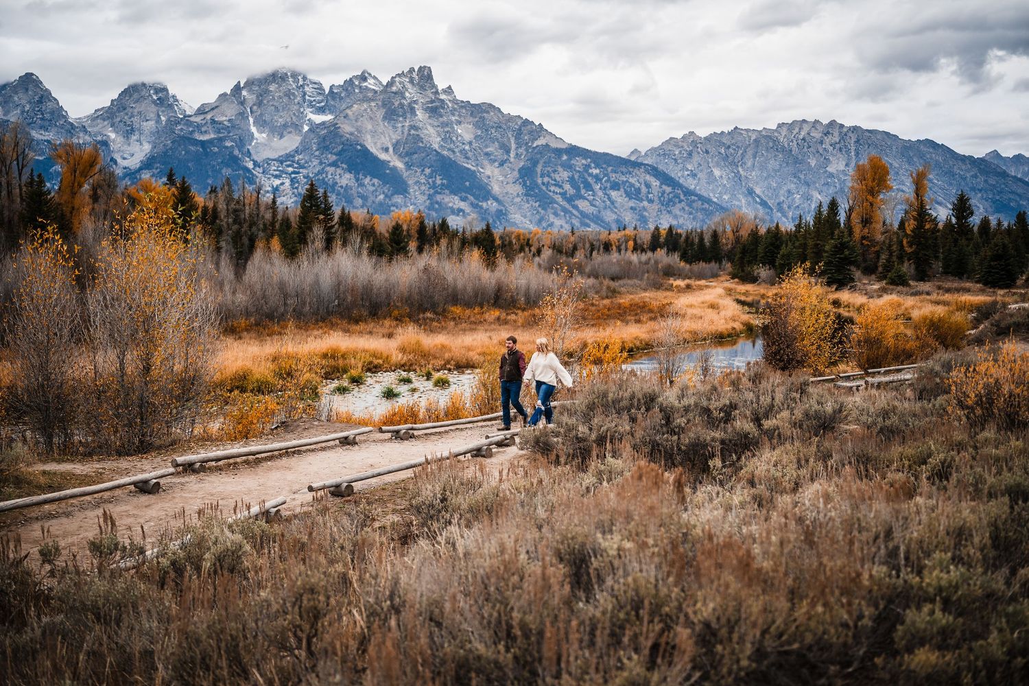 A panoramic mountain landscape with snow-capped peaks and autumn foliage in Grand Teton National Park.