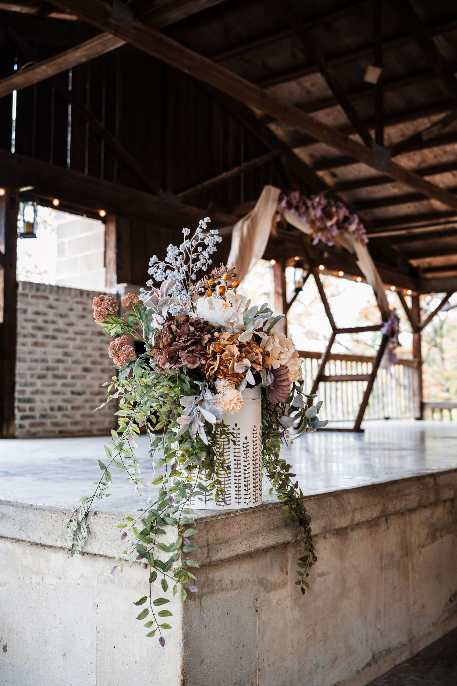 Rustic wedding venue decorated with elegant floral arrangements and string lights hanging from wooden beams.