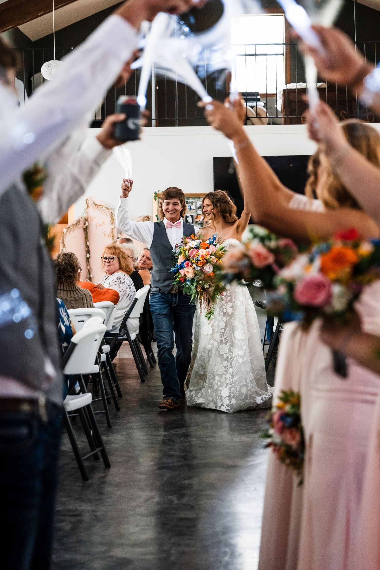Newlyweds walk down aisle while guests hold up phones to capture the celebratory moment.