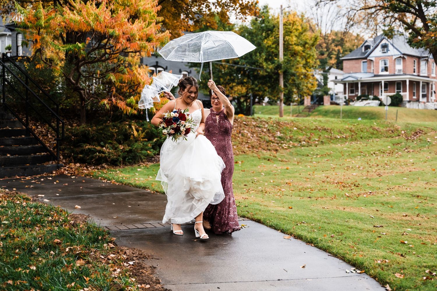A couple poses with umbrellas during an autumn outdoor wedding photoshoot.