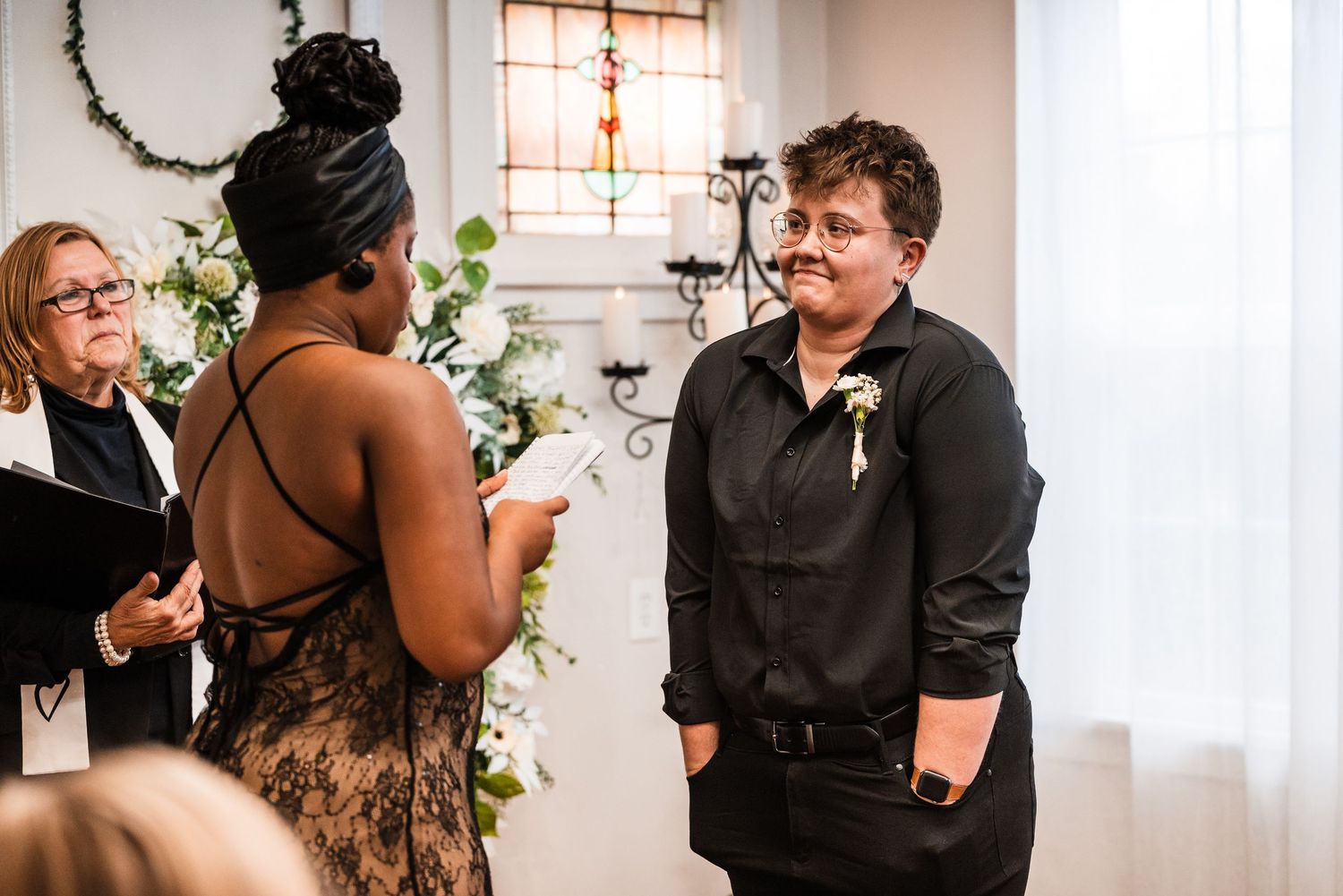 Wedding ceremony with couple exchanging vows in front of officiant with floral decorations.