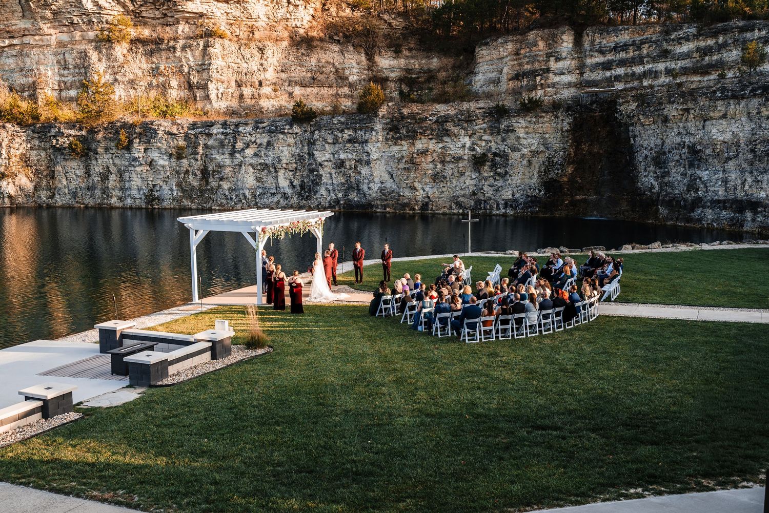 Outdoor wedding ceremony setup with chairs facing limestone cliffs near a waterfront.