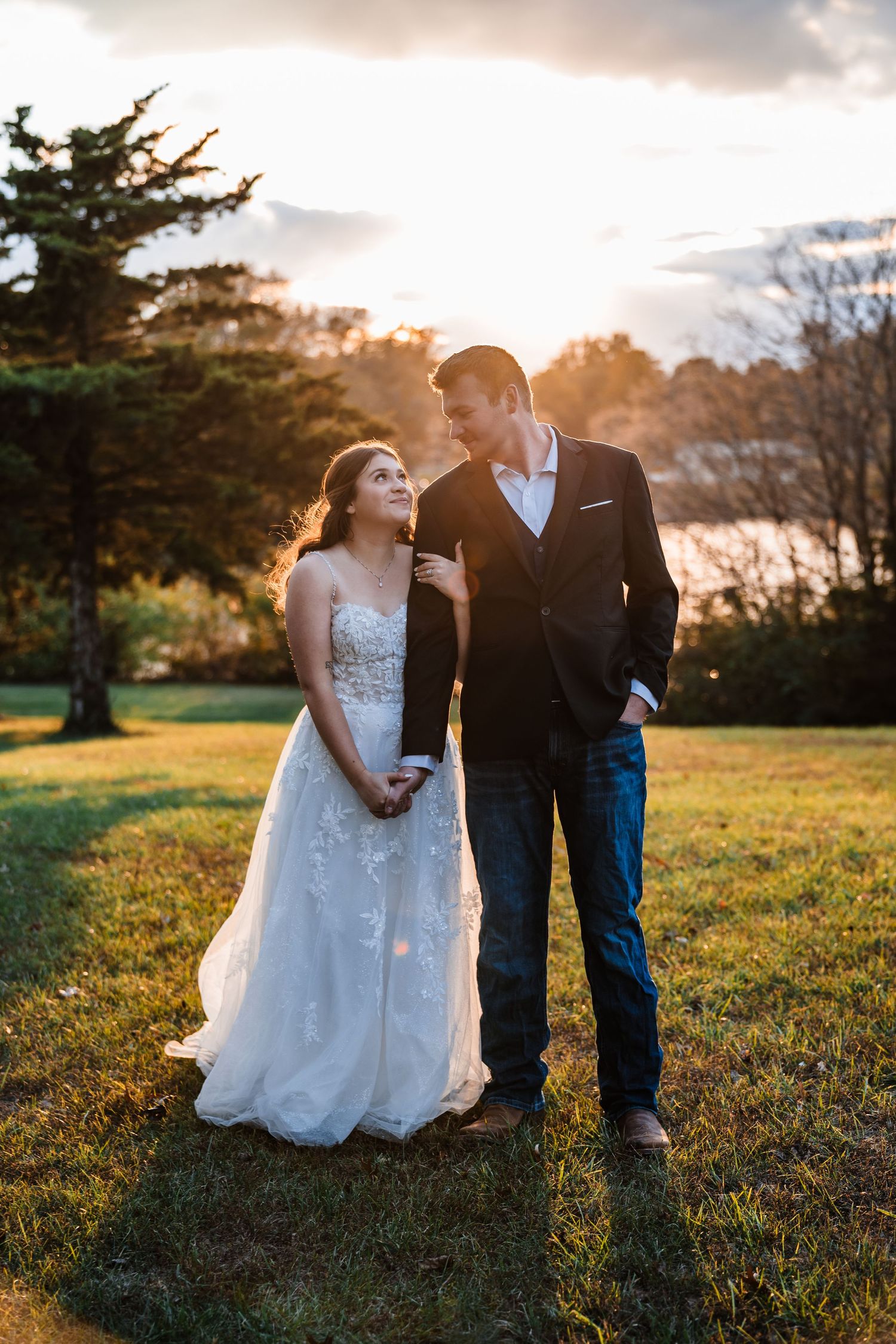 Romantic couple shares intimate moments in a golden sunlit field at sunset during their wedding photoshoot.
