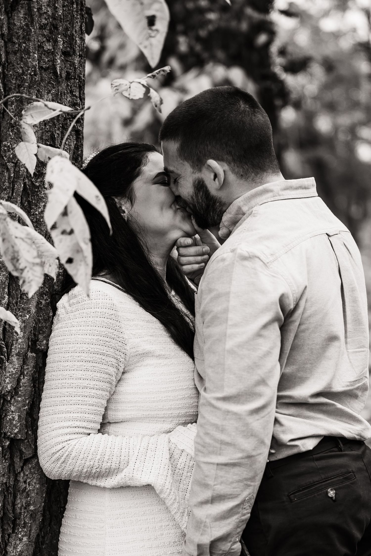 Black and white romantic portrait of couple by tree.