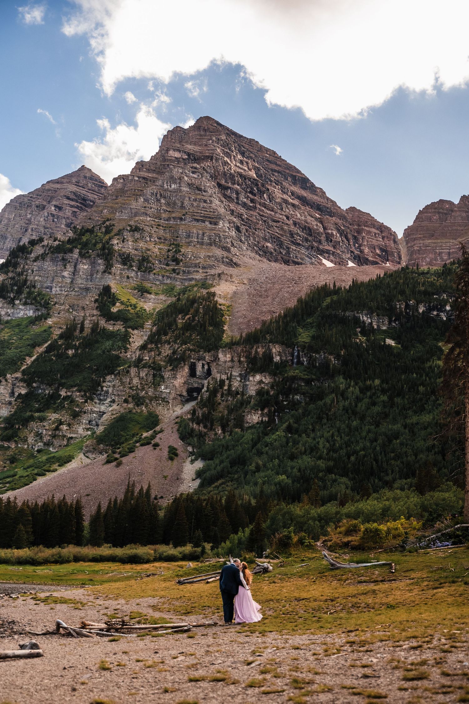 Tiny couple dwarfed by massive mountain peaks during their intimate wedding ceremony.
