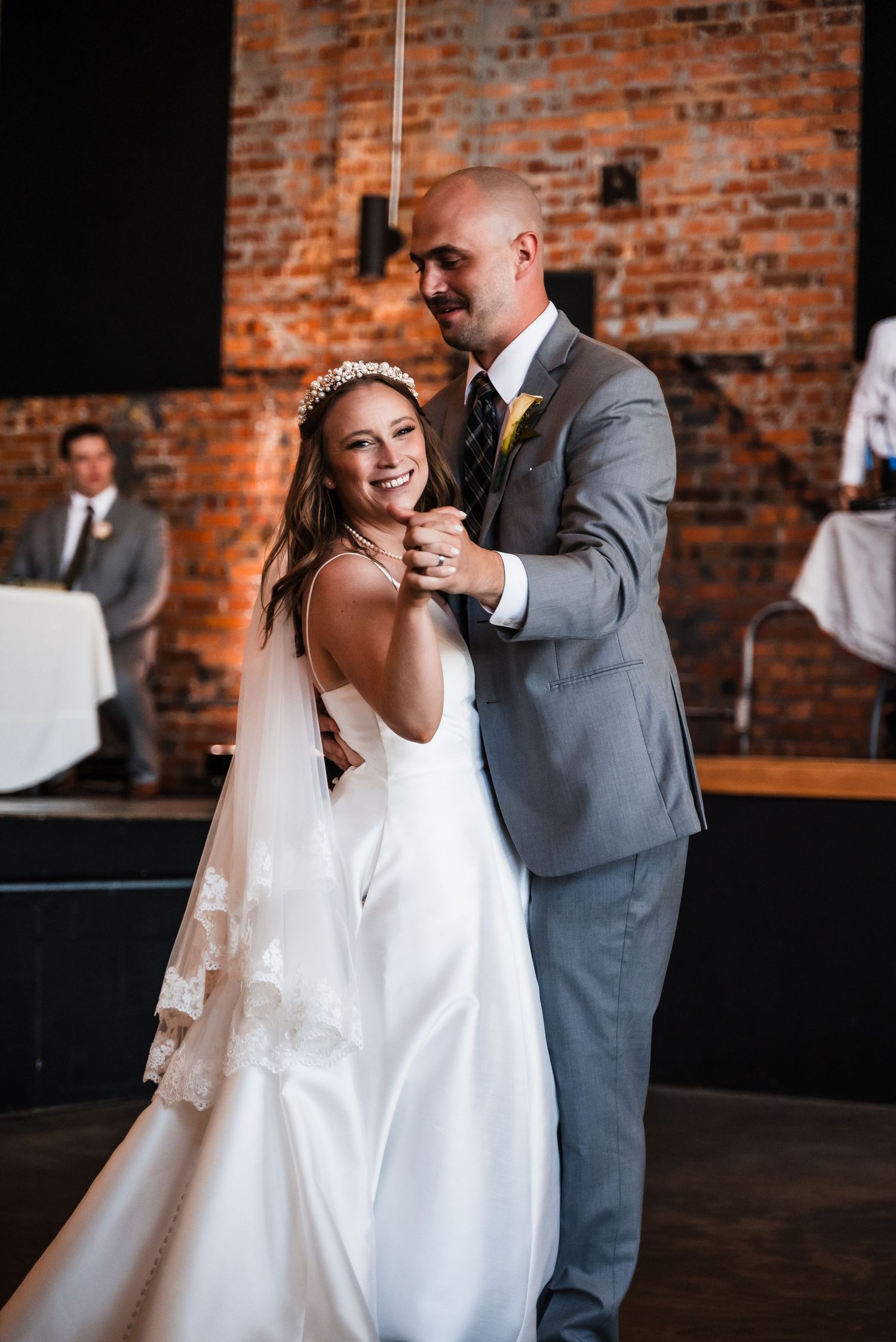 A couple shares their first dance at a rustic brick venue during their wedding celebration.