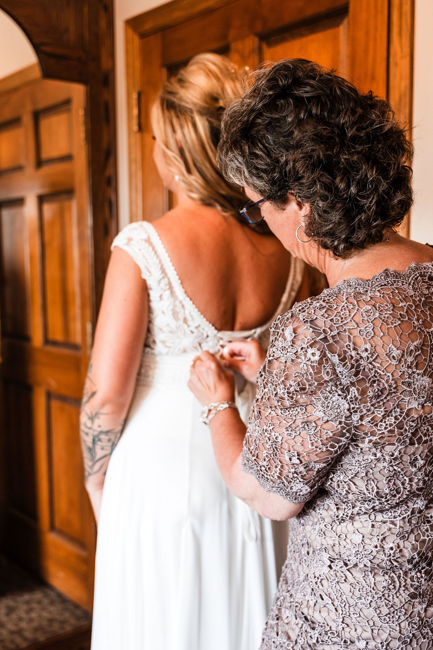 An elegant white wedding dress being buttoned up in preparation for the ceremony.