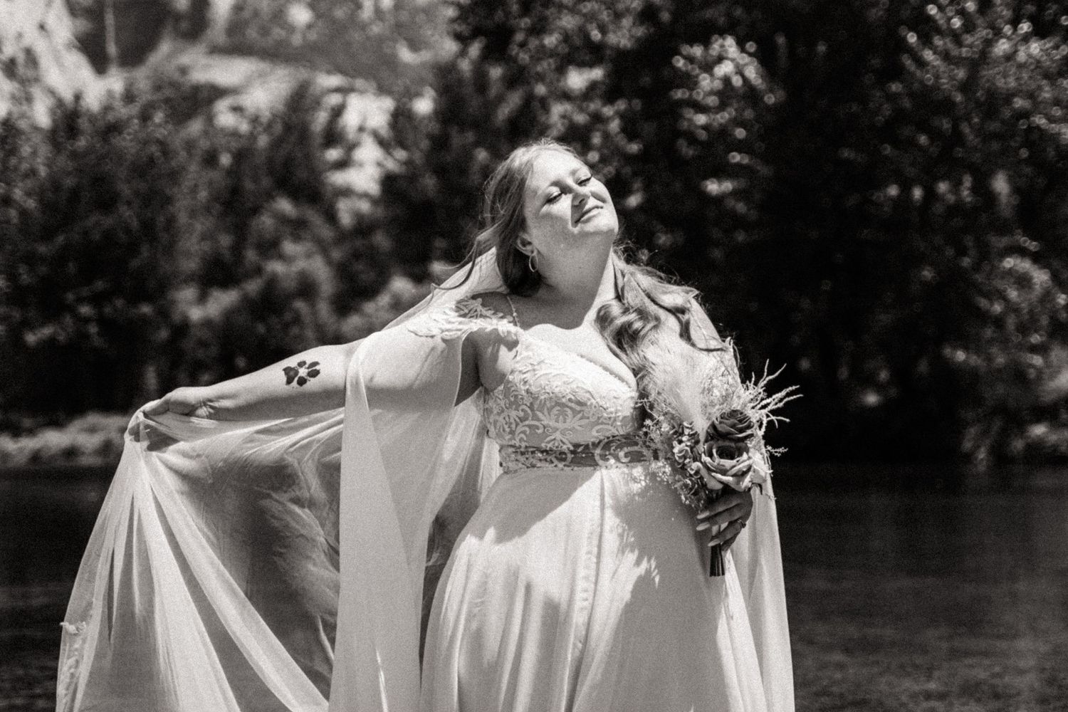 A bride with a white cape dress spins joyfully in a garden setting for wedding portraits.