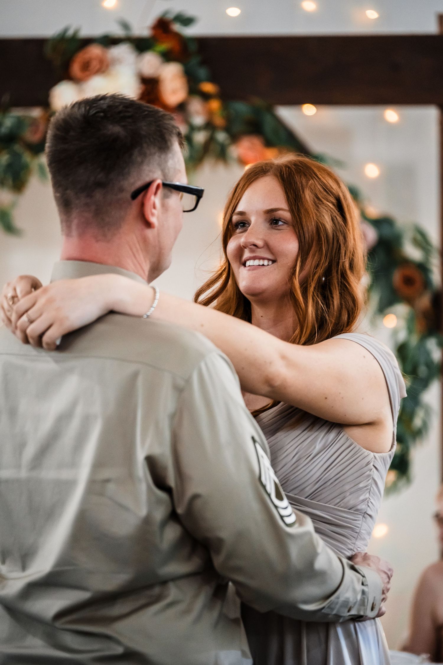 Happy couple sharing a romantic dance moment under string lights and greenery decorations.