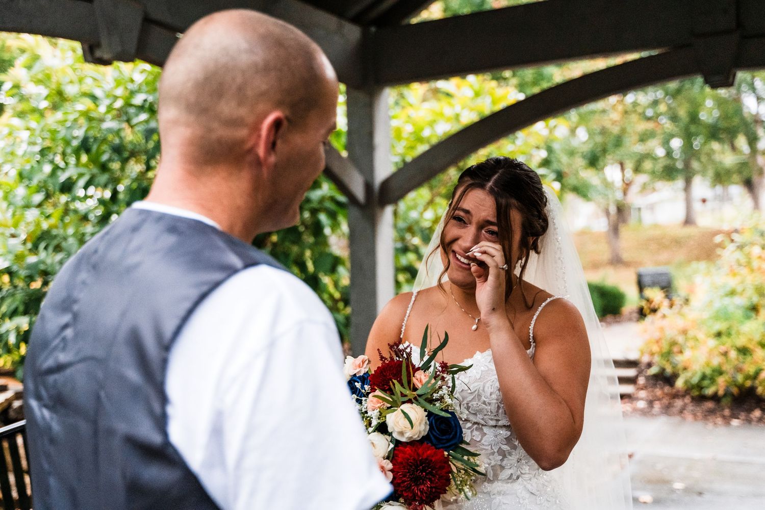 A couple shares an intimate moment under a garden pavilion during their wedding.