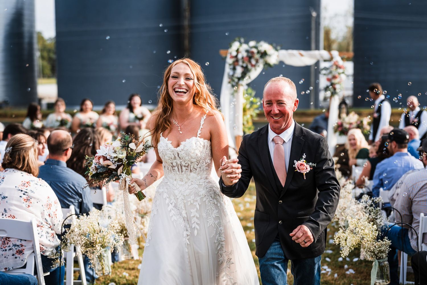 Wedding party celebrates outdoors with guests holding sparklers during an evening celebration.