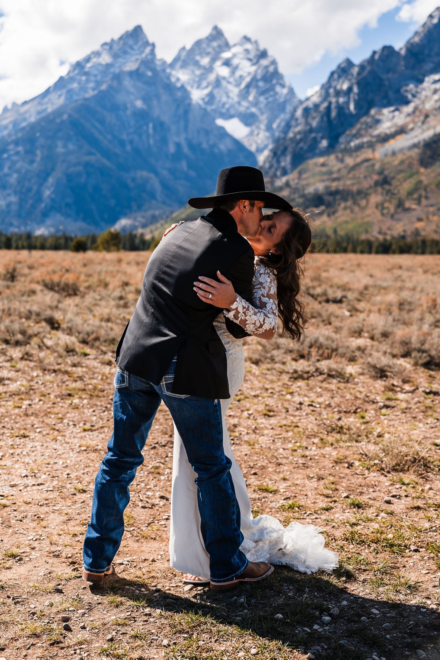 A romantic embrace between newlyweds against the dramatic backdrop of the Teton mountain range.