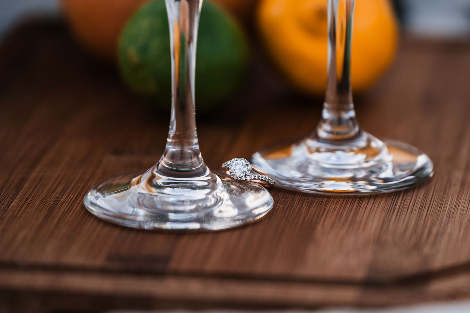 Close-up view of wine glass stems on a dark wooden table with warm lighting.