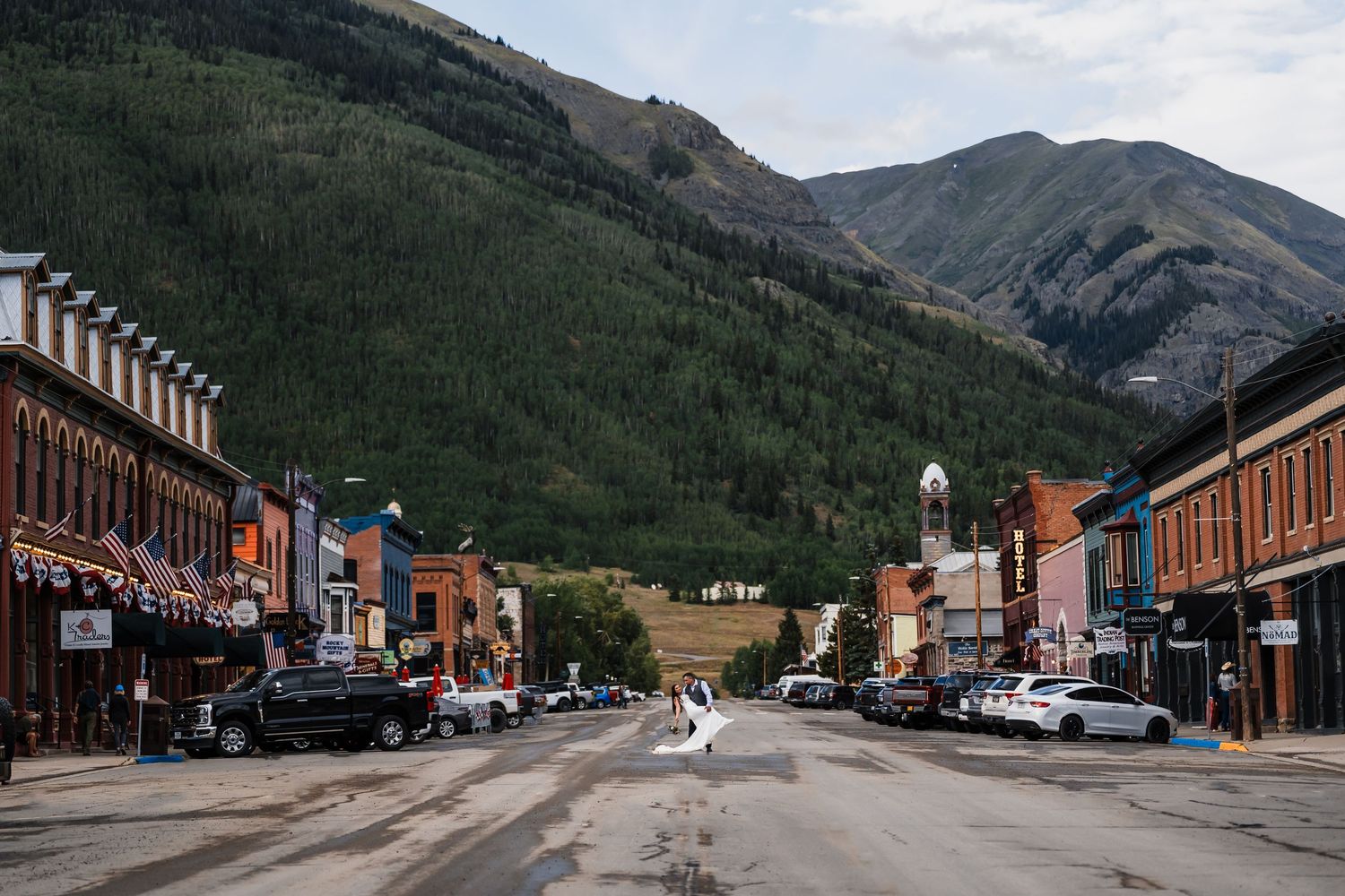 Charming mountain town main street lined with historic buildings and a dramatic hillside backdrop.