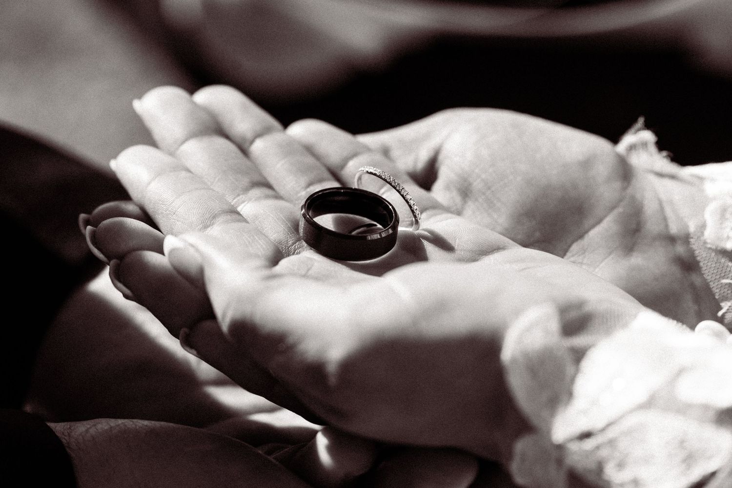 A close-up view of hands exchanging wedding rings during a marriage ceremony.