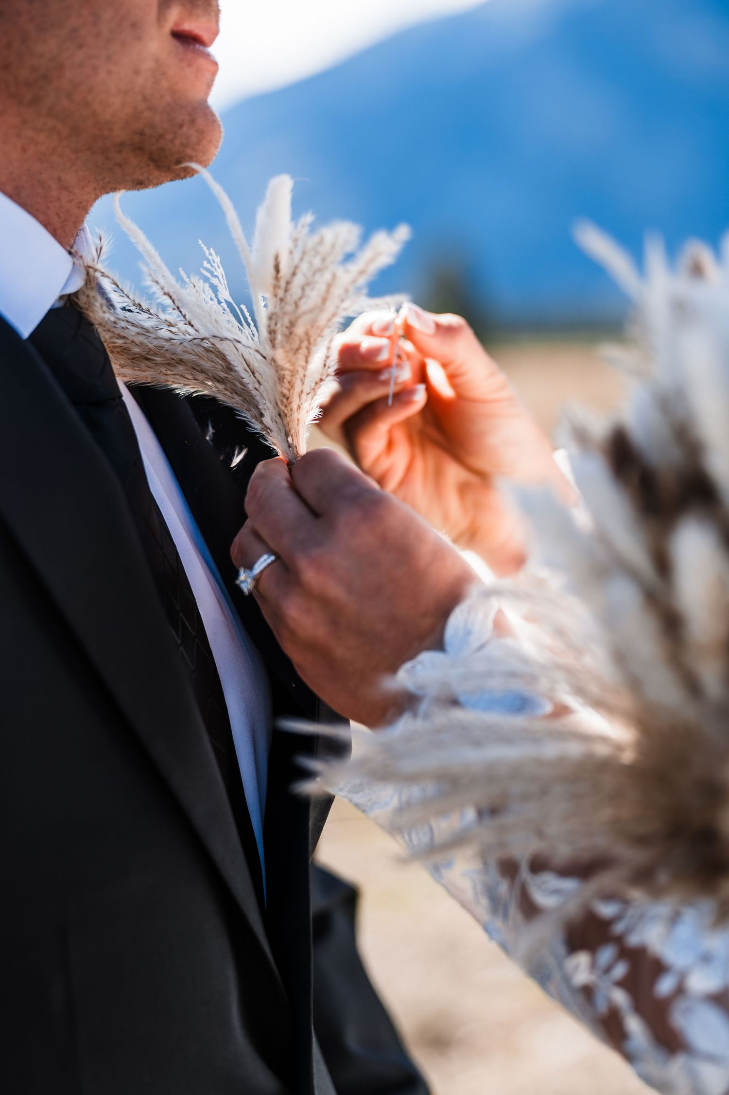 Close-up detail of someone wiping tears during an emotional moment against a blue mountain sky.